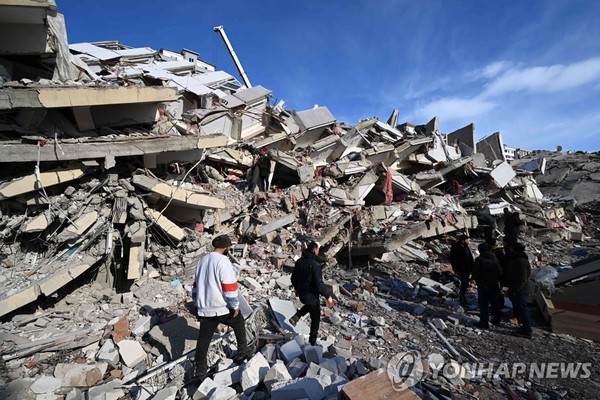 튀르키예 지진 희생자들의 친지들이 방괴된 건물 잔해에서 망연자실한 모습으로 서 있다. [AFP=연합뉴스]출처 : 인천in 시민의 손으로 만드는 인터넷신문(http://www.incheonin.com)