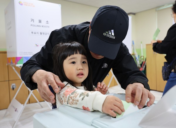 22대 총선 투표일인 10일 인천 미추홀구 용현여중의 용현5동 제6투표소에서 한 어린이가 투표용지를 투표함에 넣고 있다. 사진=연합뉴스
