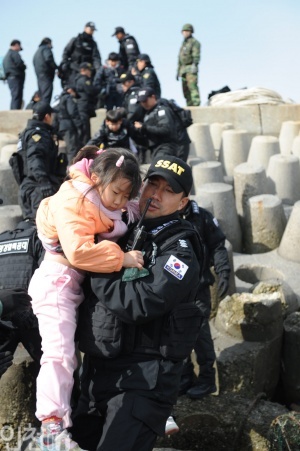 지난 24일 연평도 주민들이 인천으로 피난 온 가운데, 해경이 한 아이를 배에 태우려고 안아 올리고 있다.(사진=해양경찰청)